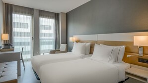 A hotel room with two beds, a desk, and a chair.