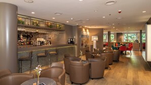 A modern bar area with leather seating, a bar counter with glasses, and a view of the outdoors.