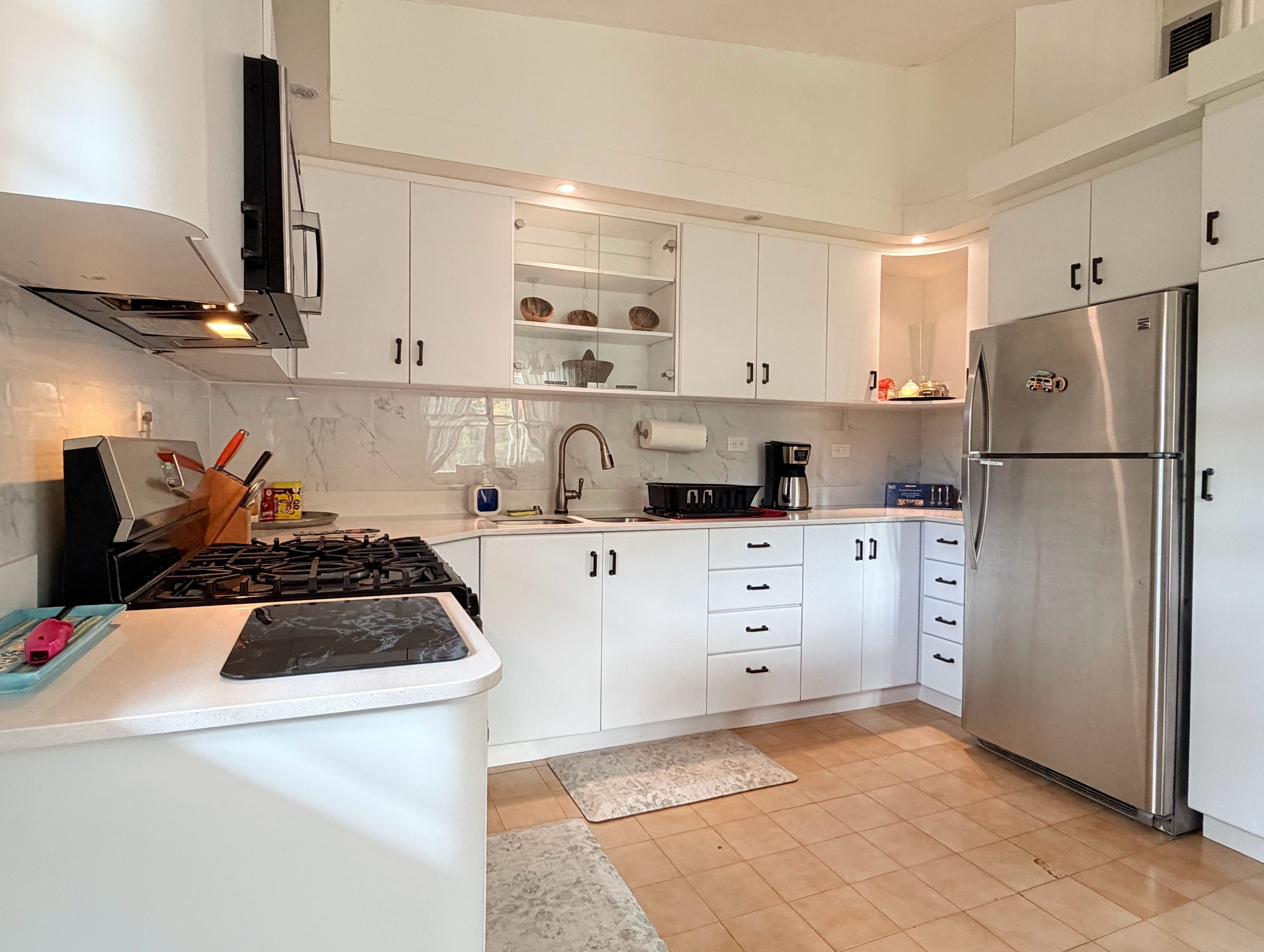 A modern kitchen with white cabinets, a stainless steel refrigerator, and a gas stove.