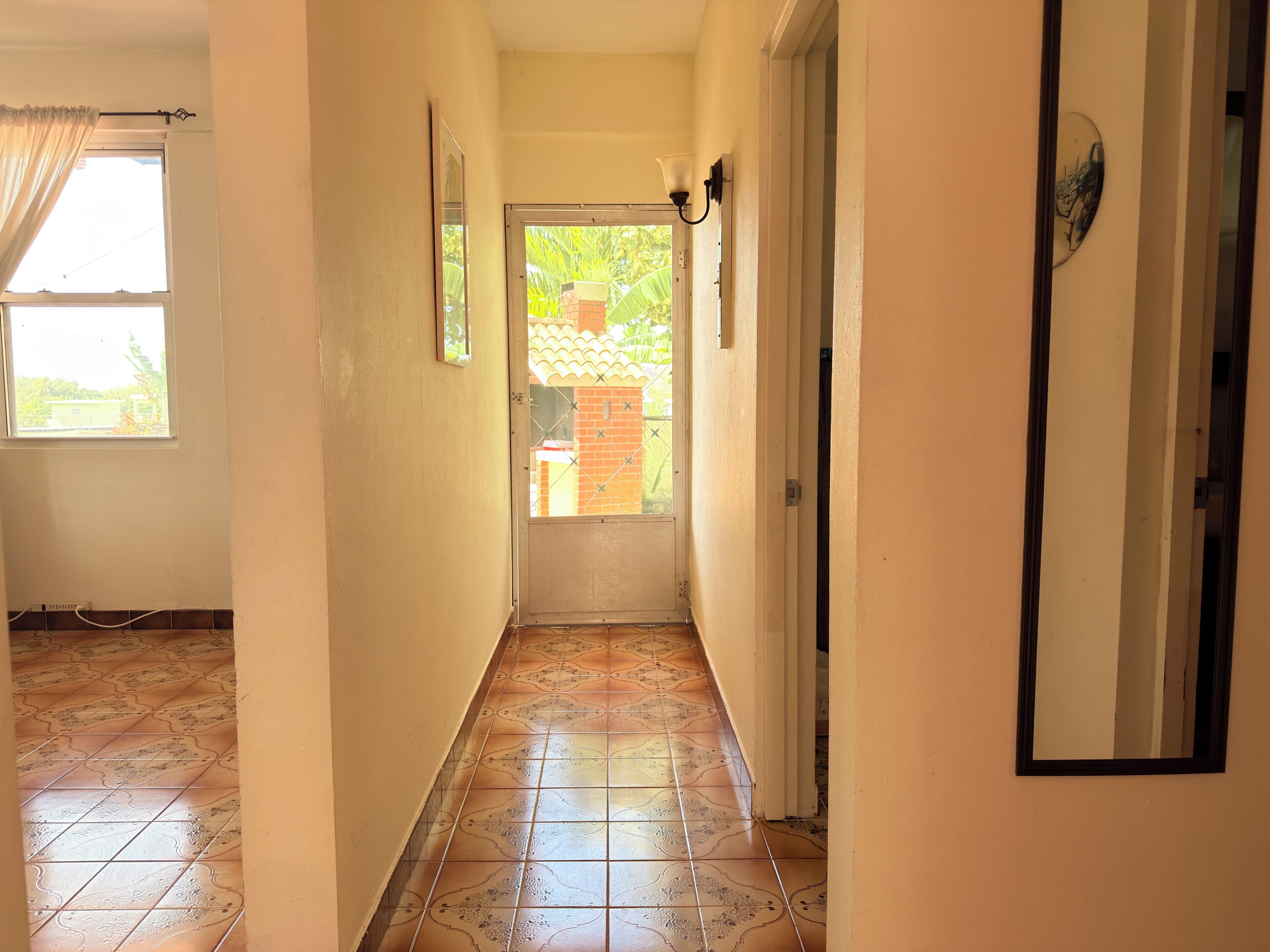 A hallway with tiled flooring, a door leading outside, and a window on the left.