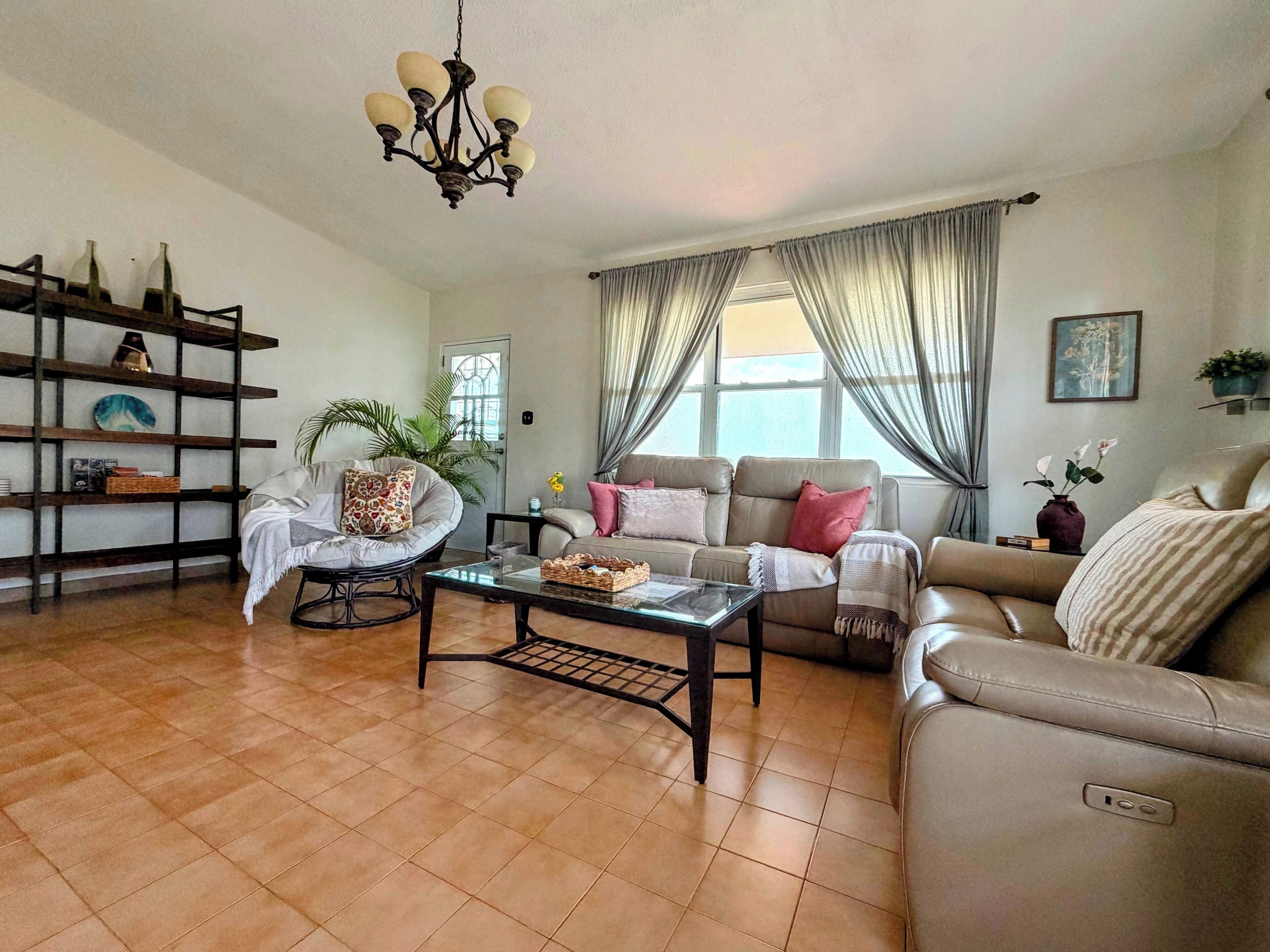 A living room with a sofa, armchairs, a coffee table, and a chandelier.