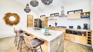 Una cocina moderna con una isla de mármol, armarios de madera e iluminación colgante.