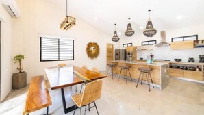 Una cocina moderna con una mesa de comedor de madera, taburetes de bar, lámparas colgantes y una isla integrada.