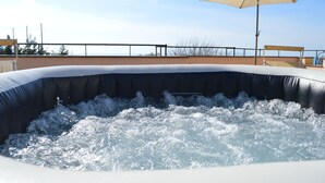 Ein Whirlpool mit Wasserstrahlen, einem Sonnenschirm und Blick auf den Himmel.