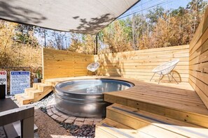 A hot tub area with wooden steps leading to it, surrounded by a wooden deck and a covered seating area. - Heated Pool + 5 min to UT/Football Stadium (Austin)