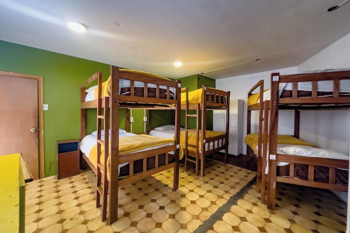 A room with bunk beds, a green wall, and a tiled floor.