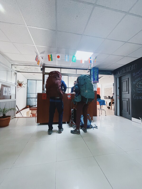 A reception area with a counter, a sign reading "DEATH ROAD," and a flag display above. - Lobo Hostel La Paz (La Paz)