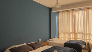 A hotel room with two beds, a ceiling fan, and a window with sheer curtains.