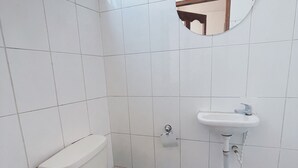 A small bathroom with a toilet, sink, and mirror.