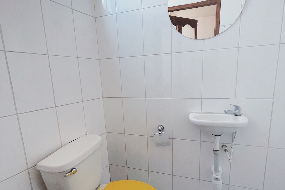 A small bathroom with a toilet, sink, and mirror.