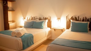 Deux lits avec des têtes de lit assorties, une table de chevet et un luminaire fixé au mur.