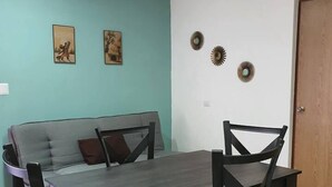 Un espace repas comprenant une table et des chaises, un canapé et des éléments de décoration murale.