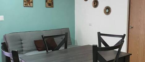 Un comedor con mesa y sillas, un sofá y adornos en la pared.