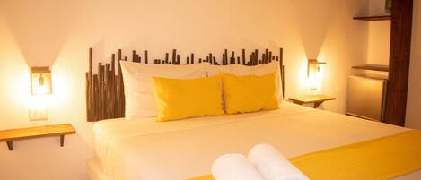 A hotel room with a bed, two bedside tables, a nightstand, and a wall-mounted shelf.
