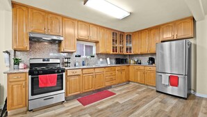 A kitchen with wooden cabinets, stainless steel appliances, and a red rug. - Spacious Home in the heart of the Bay (Oakland)