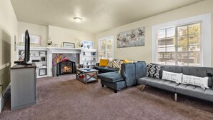 A living room with a fireplace, a sofa set, and a television. - Spacious Home in the heart of the Bay (Oakland)