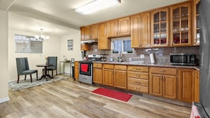 A modern kitchen with wooden cabinets, granite countertops, a stainless steel oven, and a microwave. - Spacious Home in the heart of the Bay (Oakland)