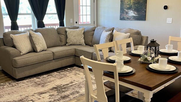 A living room with a sectional sofa, dining table with chairs, and a rug. - Cozy Sunset Retreat with a Beautiful Mountain View!  (Franklin)