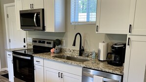 A modern kitchen with white cabinets, stainless steel appliances, and a granite countertop. - Cozy Sunset Retreat with a Beautiful Mountain View!  (Franklin)