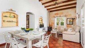 Un vaste espace de vie comprenant une table à manger, des chaises blanches, un canapé et une cheminée.