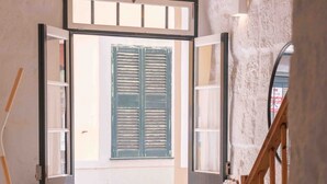 A room with a wooden chair, a small table, a round rug, and a staircase with a wooden railing. - Pere Alcantara 40, 3 bedroom house, Ciutadella (Ciutadella de Menorca)