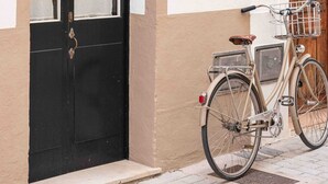 A beige building with a black door and a wooden door to the right. A bicycle with a basket is parked in front. - Pere Alcantara 40, 3 bedroom house, Ciutadella (Ciutadella de Menorca)