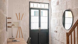 A rustic room with a stone ceiling, a wooden desk with a laptop, a black door, and a round mirror. - Pere Alcantara 40, 3 bedroom house, Ciutadella (Ciutadella de Menorca)