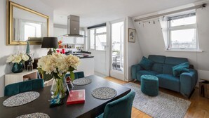 A modern living space with a dining area, a sofa, and a kitchen.