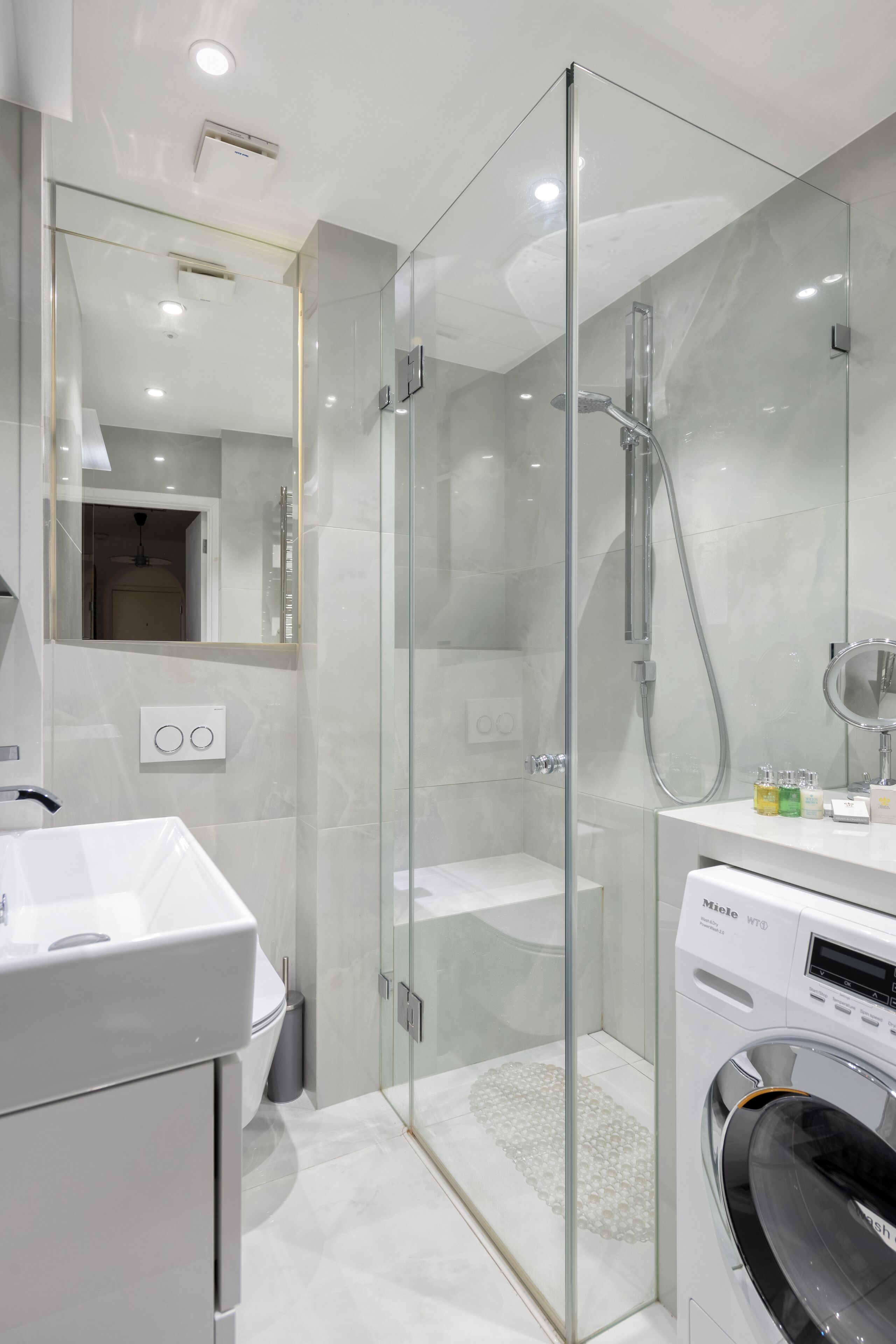 Ein modernes Badezimmer mit Duschkabine, integriertem Waschbecken und einer Frontlademaschine.