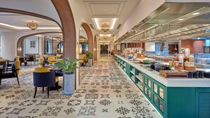 Un hall de hotel con una larga recepción, zona de estar y suelo estampado.