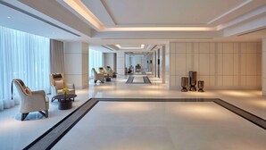 Un amplio vestíbulo de hotel con mobiliario moderno, un largo pasillo y un diseño minimalista.