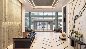 A modern lobby with a reception desk, seating area, and large windows offering views of the outside. - Hilton BNA Nashville Airport Terminal (Nashville)