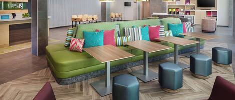 A modern hotel lobby with a green sofa, multiple tables, and comfortable seating.