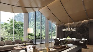 Un salon moderne doté d’une grande fenêtre, un coin repas avec un mur en pierre et un îlot central agrémenté de divers objets.
