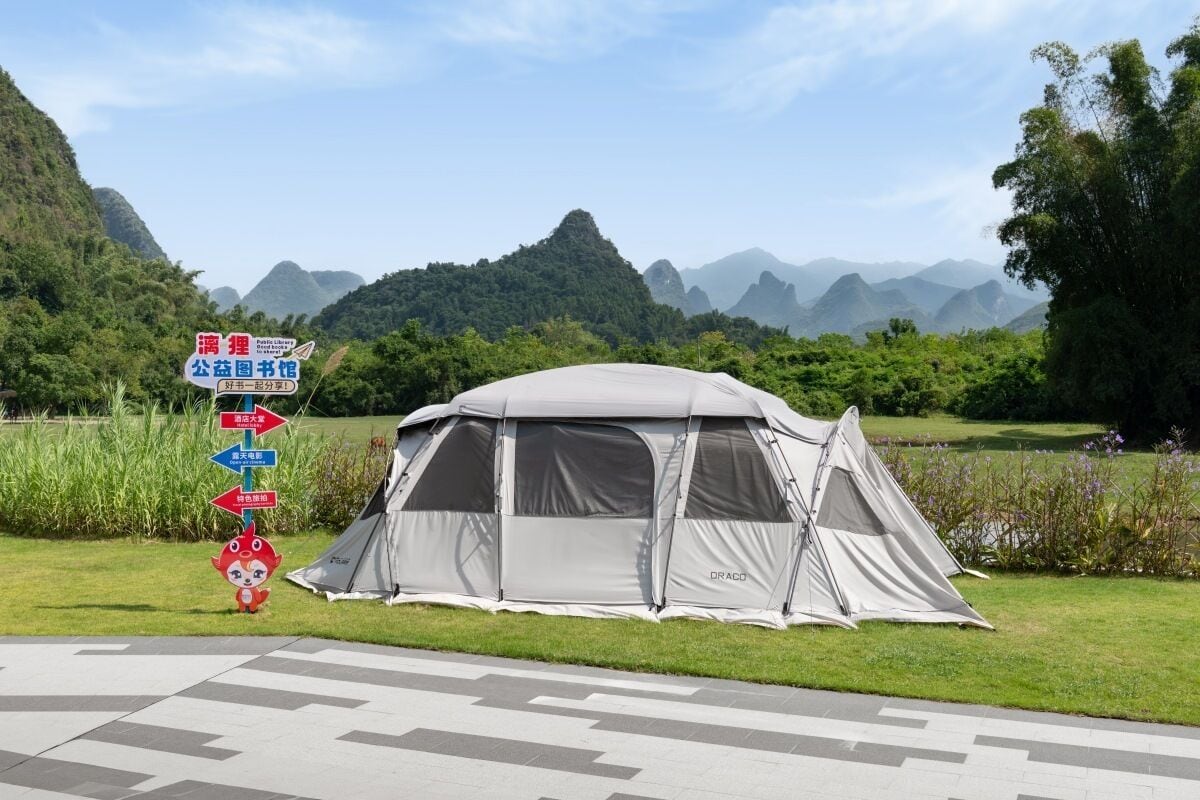 A tent set up in a grassy area with a mountainous backdrop.