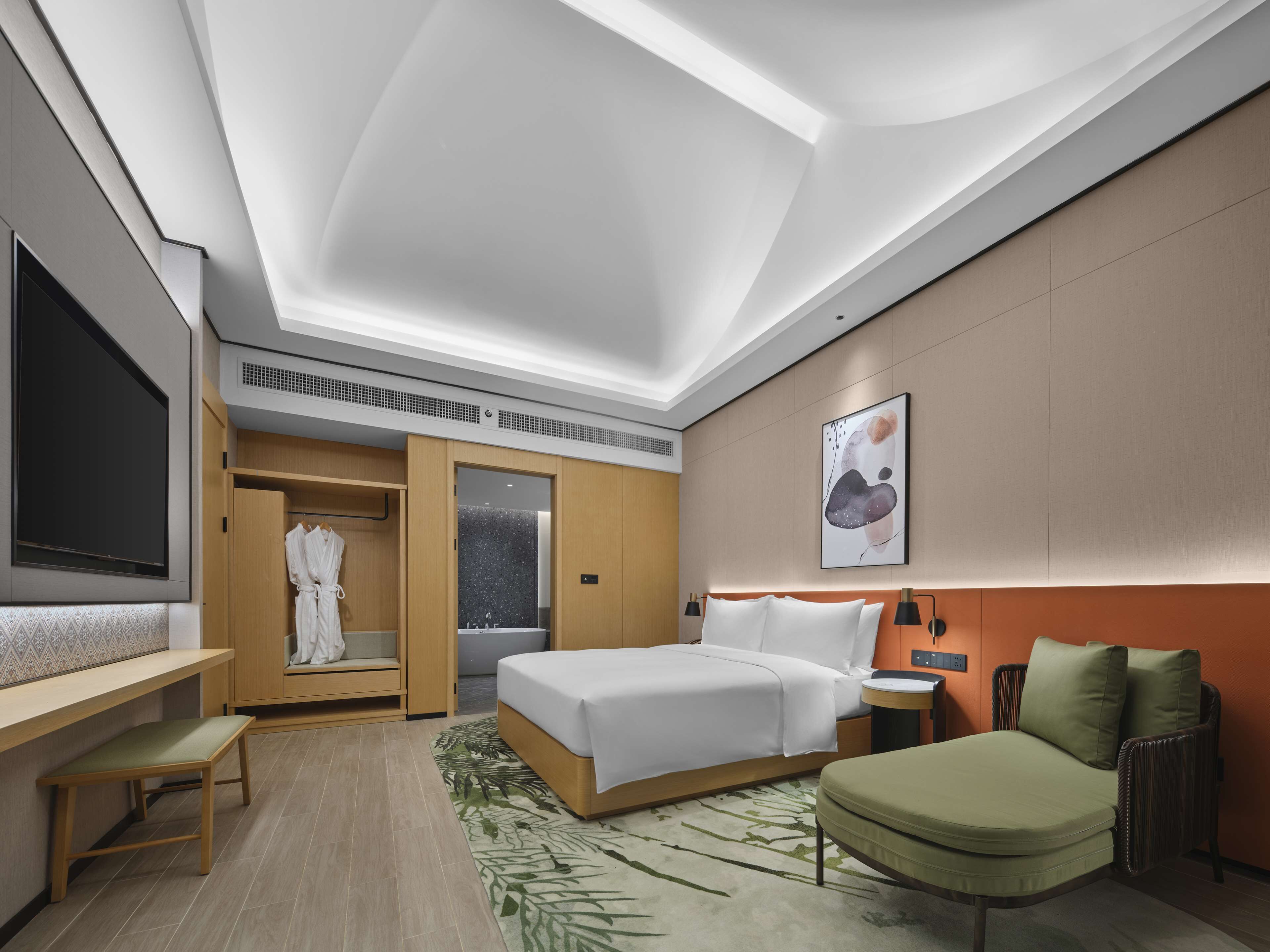Ett modernt hotellrum med en stor säng, ett skrivbord, en sittgrupp och en rymlig klädkammare.