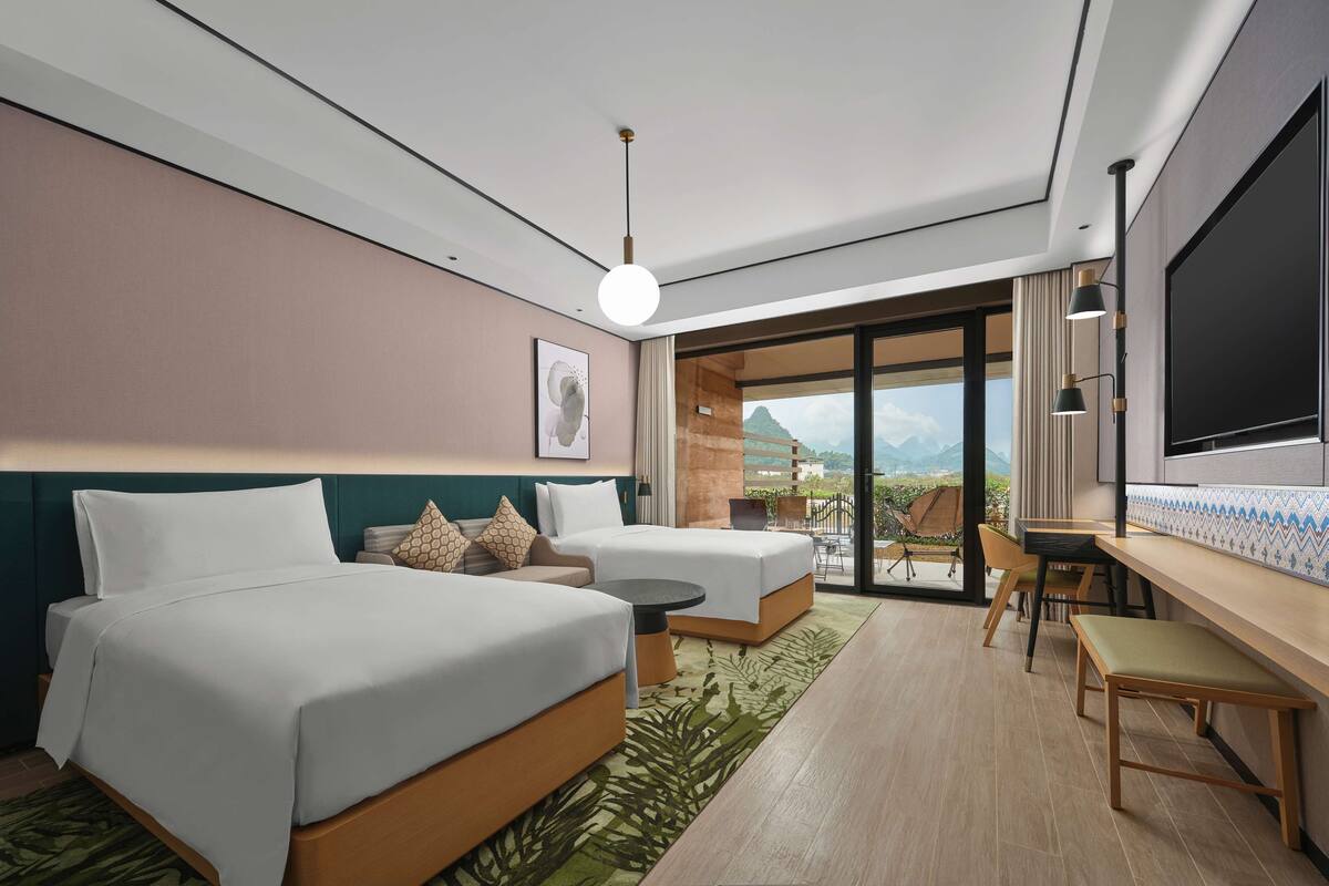 A modern hotel room with a large bed, a sofa, a desk, and a TV.