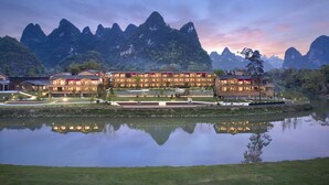 Un hôtel composé de plusieurs bâtiments, dont le reflet se mire dans l’eau, avec des montagnes en toile de fond.