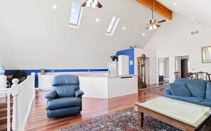 A spacious living room with a blue sofa, a leather chair, and a wooden coffee table.