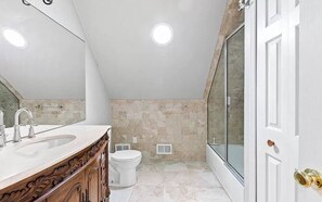 A modern bathroom with a large shower, a vanity with a sink, and a toilet.