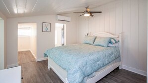 Un dormitorio con una cama, ventilador de techo y aire acondicionado.