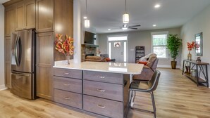 A modern kitchen with a large island, stainless steel appliances, and a dining area with a sofa and chairs. - Secluded Barboursville Home with Covered Porch! (Barboursville)