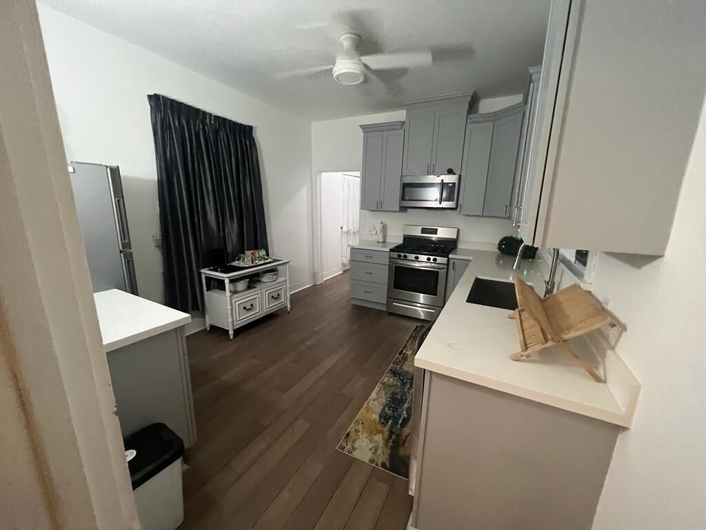 A compact kitchen with grey cabinets, a microwave, a stove, and a small countertop.