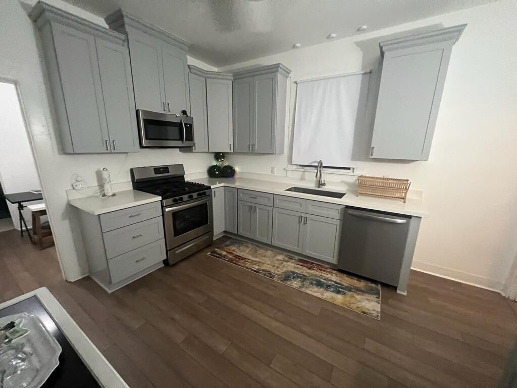 A kitchen with grey cabinets, a stainless steel microwave, a stove, and a dishwasher.