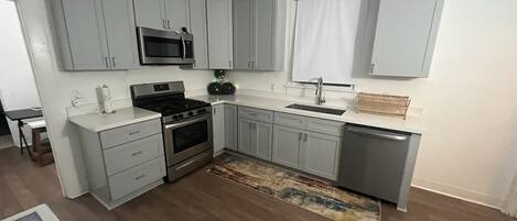 A kitchen with grey cabinets, a stainless steel microwave, a stove, and a dishwasher.