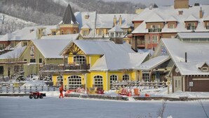 Une ville enneigée, avec des bâtiments aux couleurs vives et un télésiège.