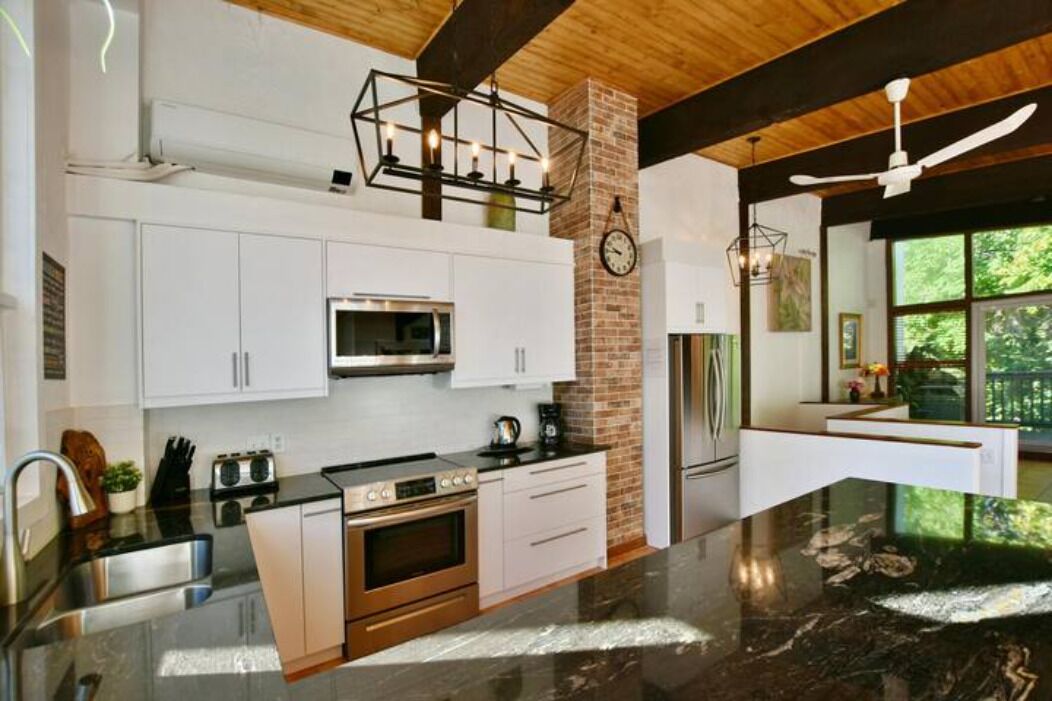 A modern kitchen with white cabinets, a stainless steel oven, and a black countertop.