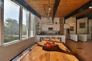 Een moderne keuken met grote ramen, een houten eettafel en een hanglamp.