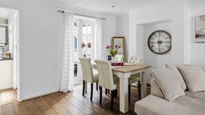 A dining area with a wooden table, white chairs, and a clock on the wall.