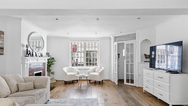 A modern living room with a sofa, two armchairs, a coffee table, a TV, and a fireplace.